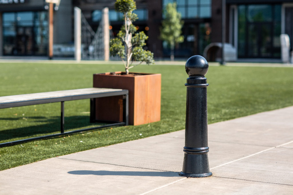 A bollard in a pedestrian path within a mixed use development.
